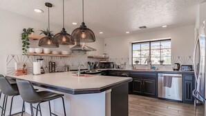 A modern kitchen with a central island, pendant lighting, and a large window providing natural light.