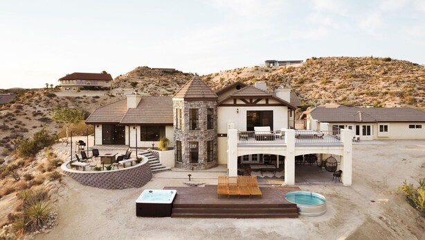 A modern multi-story house with a patio, outdoor seating, and a swimming pool.