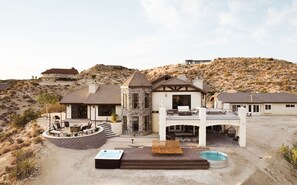A modern multi-story house with a patio, outdoor seating, and a swimming pool.