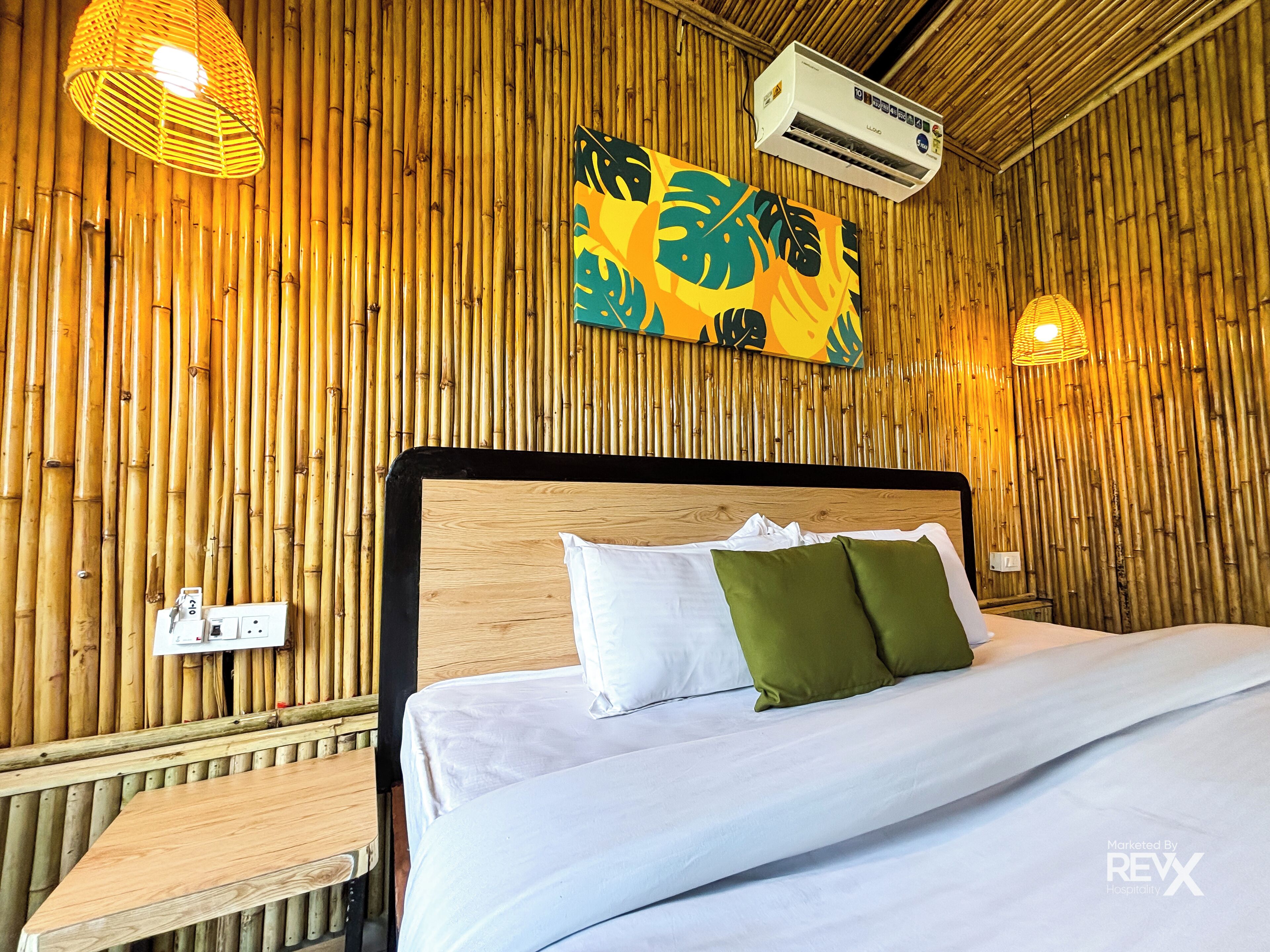 Ein Zimmer mit einem Bett, einer Wand-Klimaanlage und einer Wand mit vertikalen Bambuspaneelen.