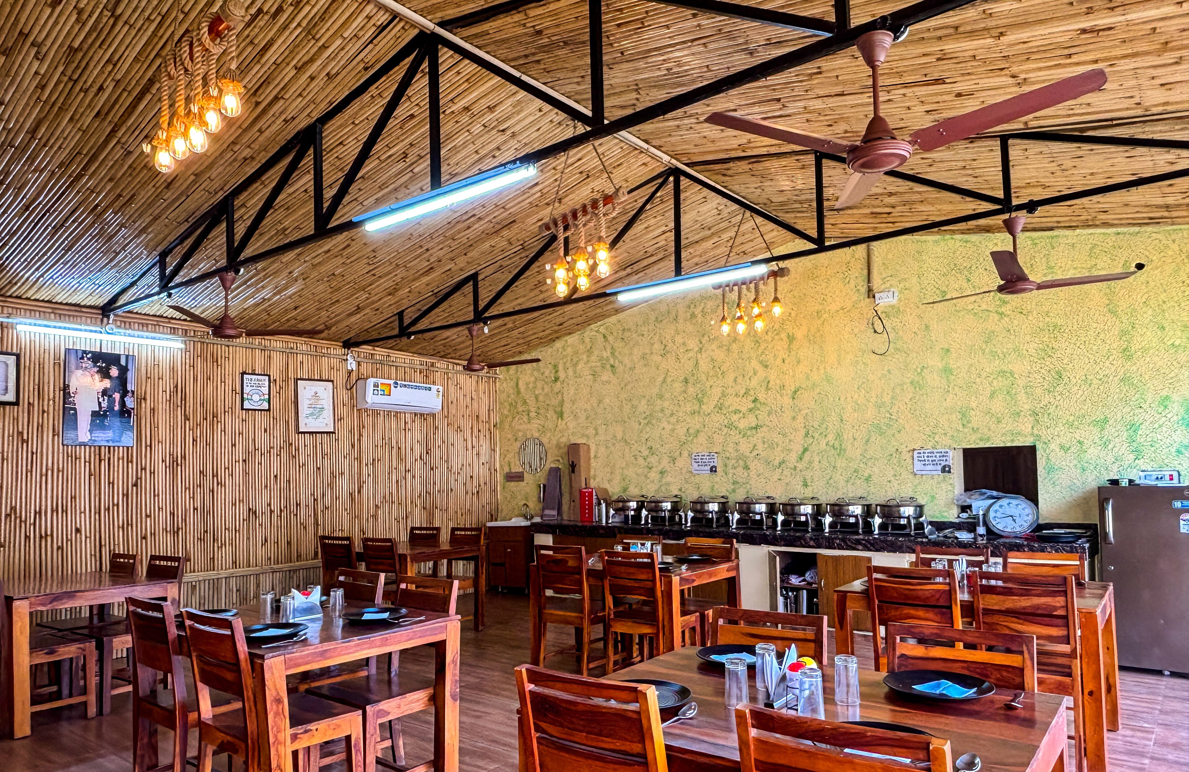 A restaurant with wooden walls, ceiling fans, and a kitchen area with cooking equipment.