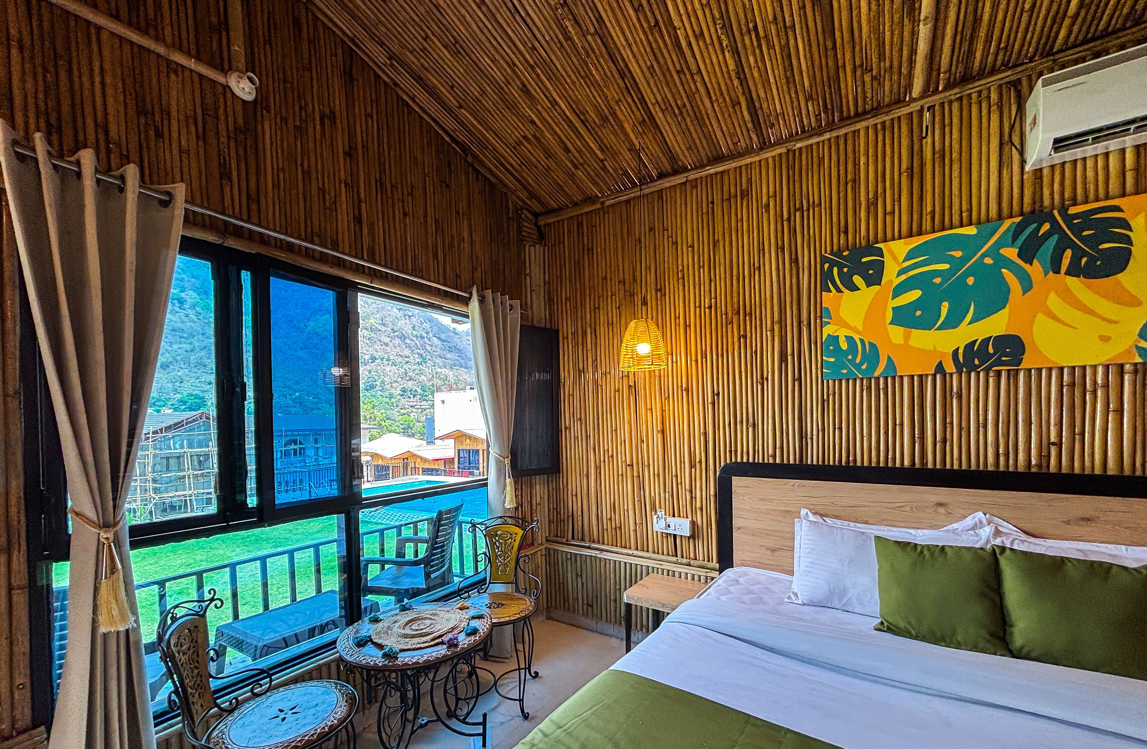 Ein Zimmer mit Bett, Tisch und Stühlen, mit Blick auf einen Pool und Berge.