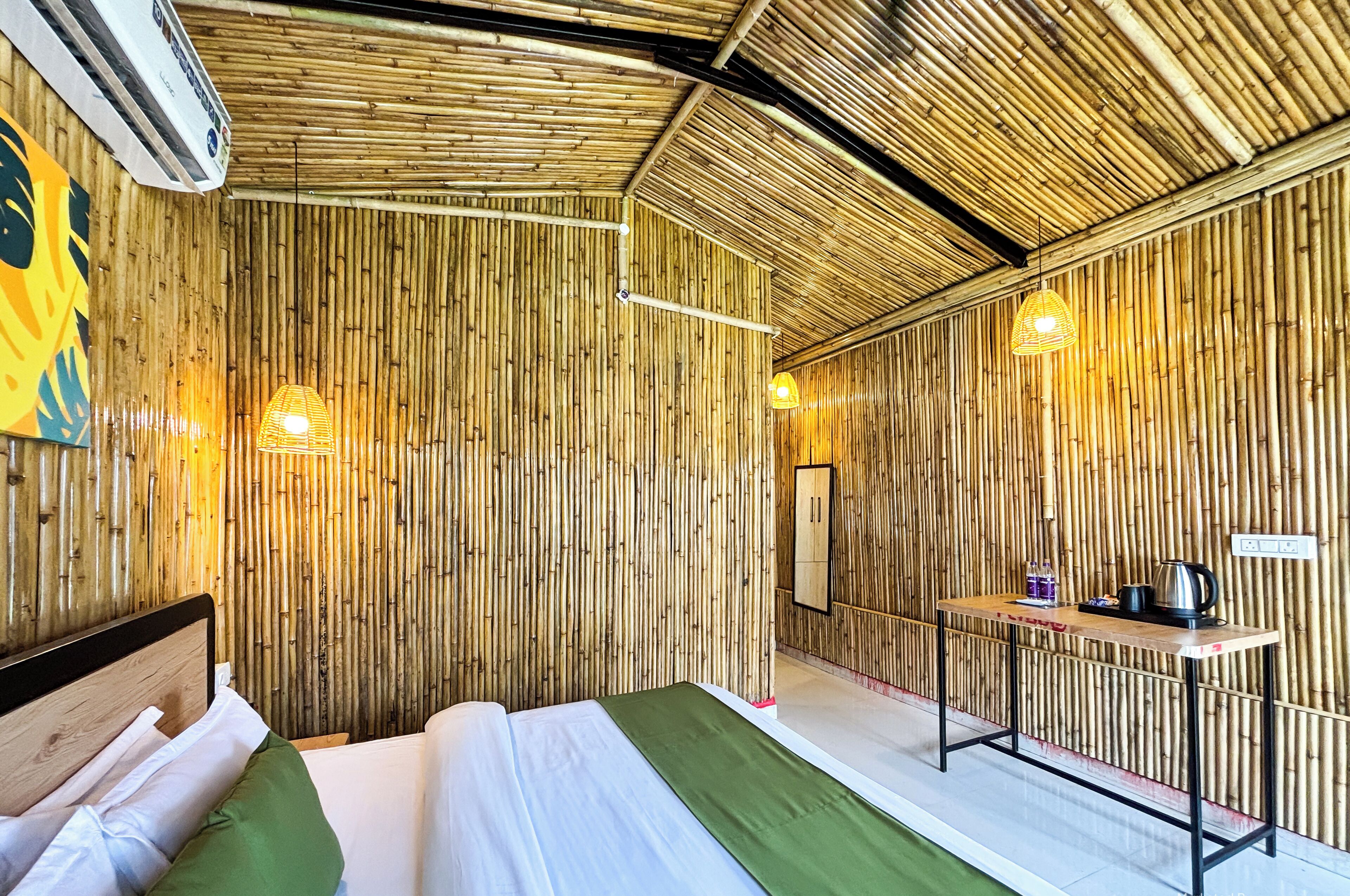 A room with a bed, a table with a kettle, and a wall with vertical bamboo panels.