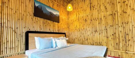A room with a bed, a nightstand, a bench, a hanging light fixture, and a wall-mounted painting.