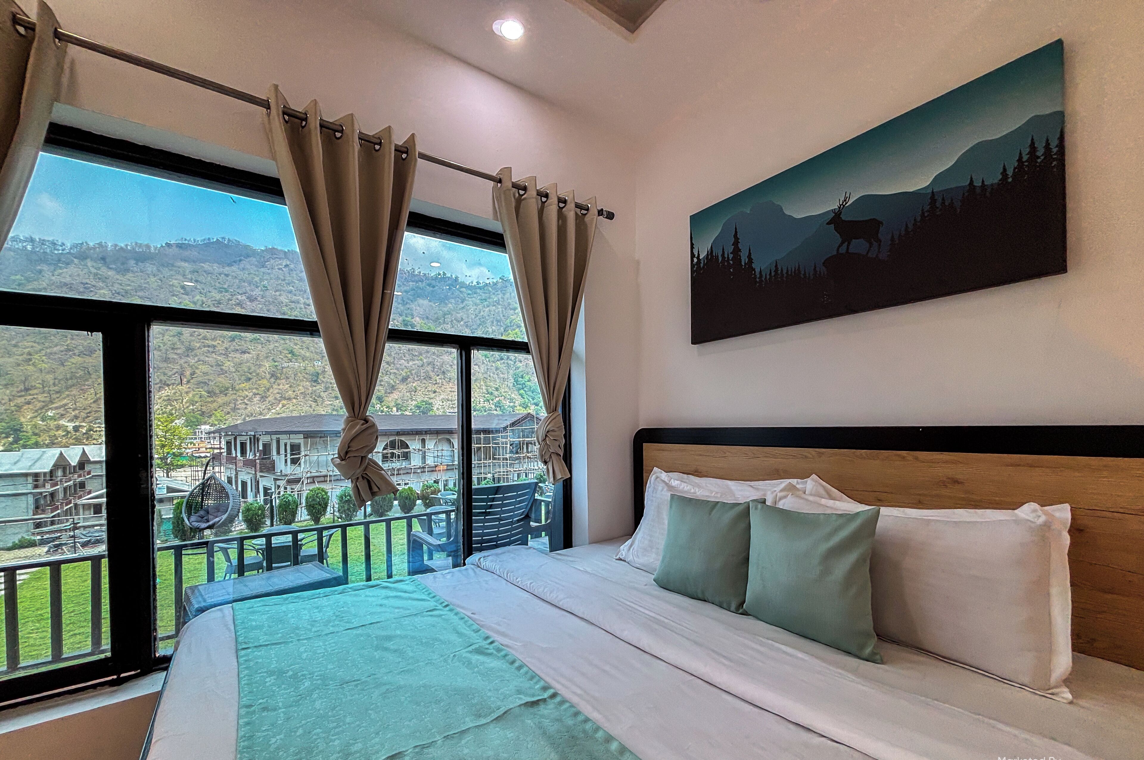 Ein Schlafzimmer mit einem großen Bett, Bergblick und einem Balkon mit Gartenmöbeln.