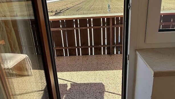 Una habitación con puerta corrediza de vidrio que da a un balcón con vista a la montaña.