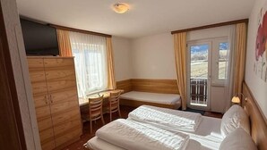 Una habitación de hotel con una cama, un escritorio, una silla, un armario y un televisor.