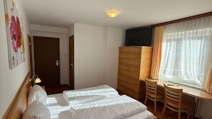 Una habitación de hotel con una cama, un escritorio, una silla y un televisor.