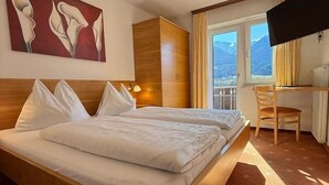 Une chambre d’hôtel avec un grand lit, un bureau, une chaise, une télévision et un tableau au mur.