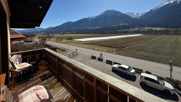 Un balcon donnant sur une route et des montagnes.