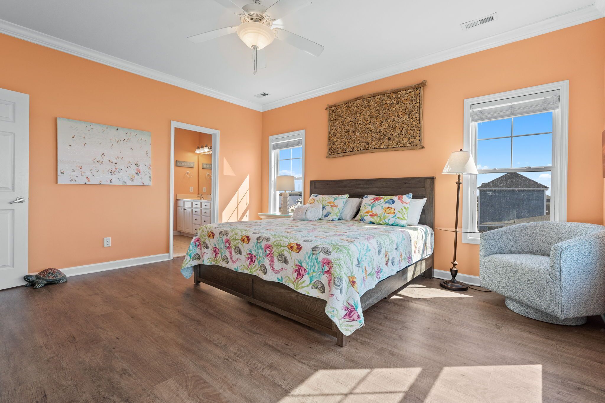 Une chambre à coucher avec un lit, un ventilateur de plafond, une chaise et une fenêtre.