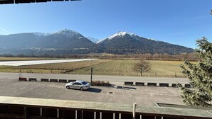 A parking area with a car, a mountain range in the background, and a clear sky.