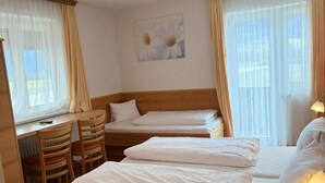 Habitación de hotel con dos camas, un escritorio y una silla.