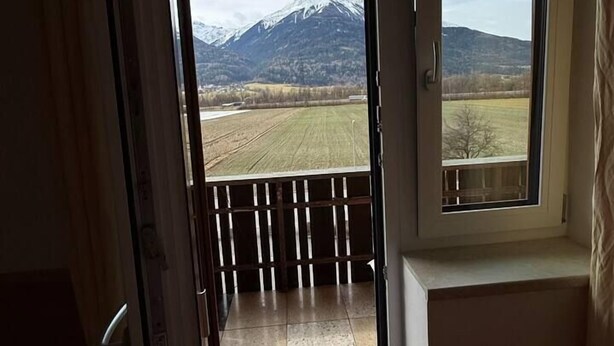 Una habitación con vista a una montaña y un campo.