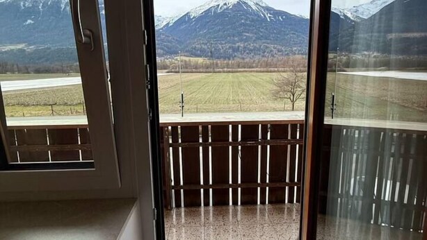 A room with a sliding glass door leading to a balcony with a mountain view.