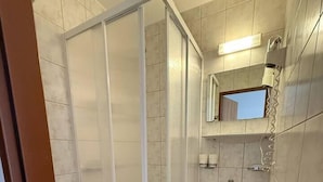 A bathroom with a toilet, a sink, a shower enclosure, and a blue bucket.