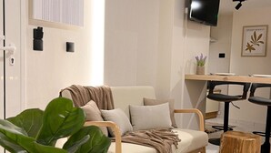 Un salon moderne comprenant un canapé, une table basse, un téléviseur et un coin repas avec des chaises.