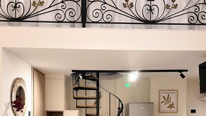 Une cuisine moderne avec un escalier en colimaçon, des meubles en bois et un coin repas agrémenté de tabourets de bar.