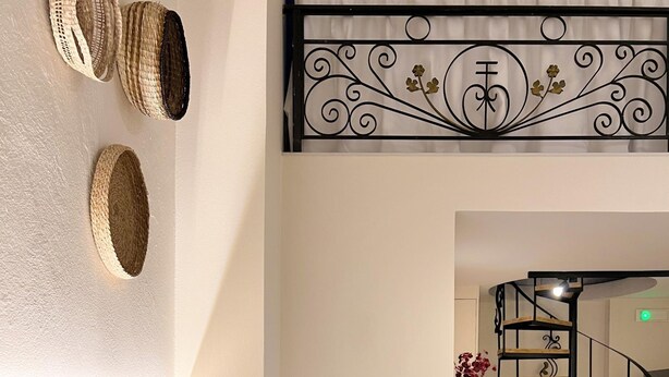 Une chambre d’hôtel avec un lit, un mur décoratif, un escalier et une petite table sur laquelle se trouve un vase.