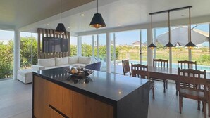 A modern kitchen with a large island, wooden cabinetry, and pendant lighting.