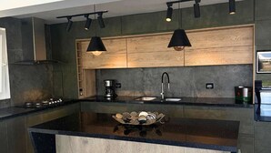 A modern kitchen with a central island, dark cabinetry, and pendant lighting.