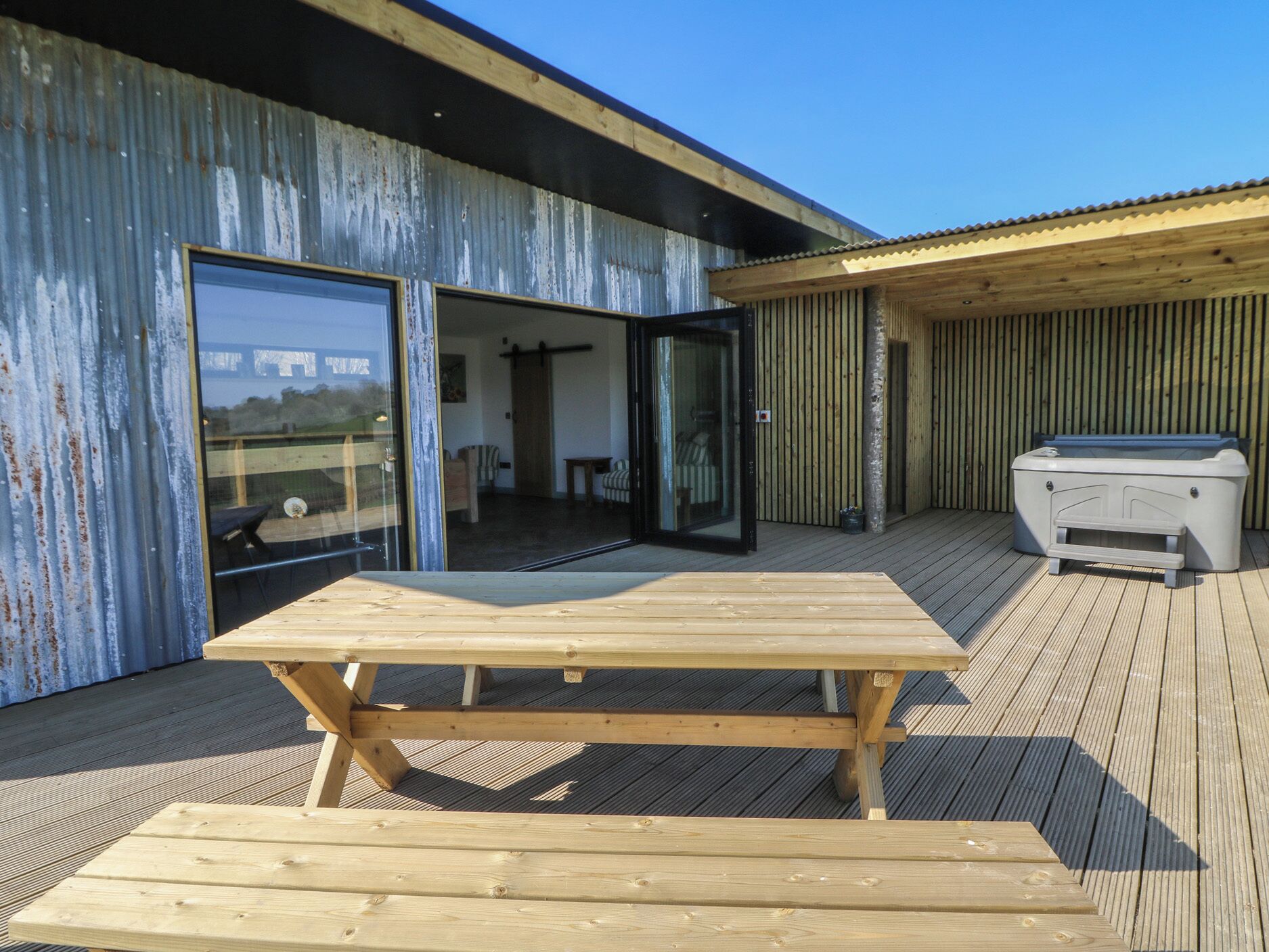A wooden deck with a table and a hot tub.