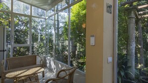A conservatory with wicker furniture and a stone pillar.