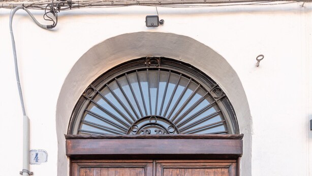 A wooden double door with a metal grill and a circular window above it. - Crispi Suite in Palermo by Wonderful Italy (Palermo)