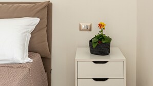 A neatly arranged bedroom with a bed, bedside table, and a hanging light fixture. - Crispi Suite in Palermo by Wonderful Italy (Palermo)