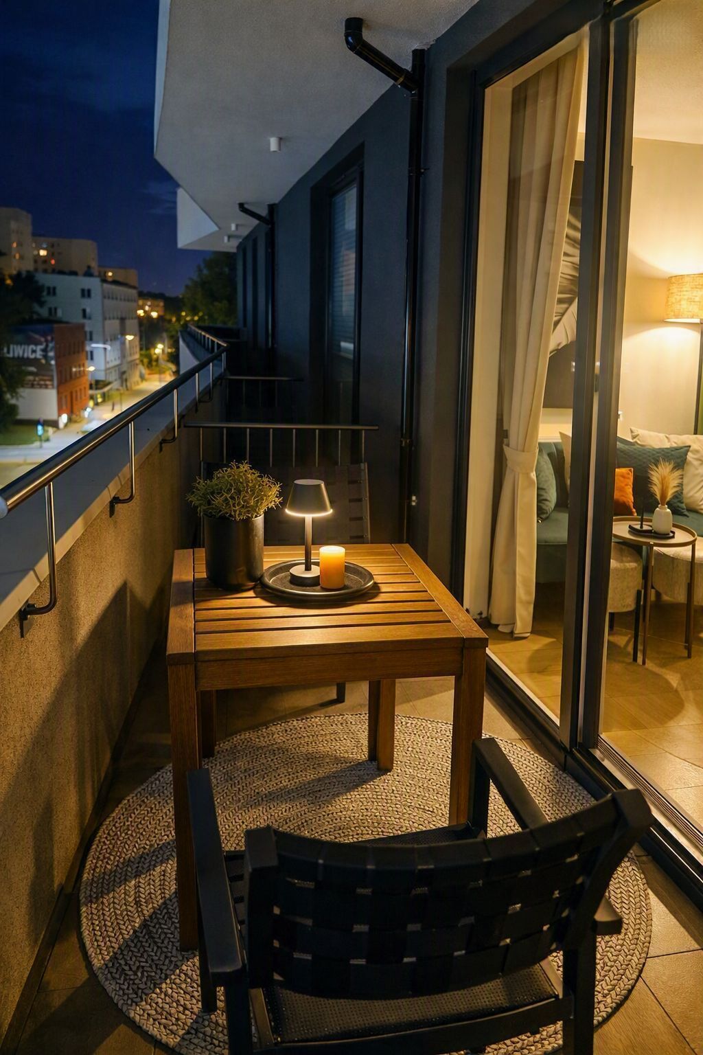 A balcony with a table, a chair, a lamp, and a candle.