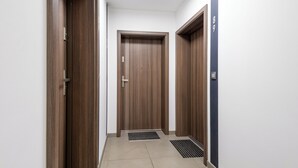 Un pasillo con tres puertas de madera, un respiradero en el piso y un interruptor de luz en la pared.