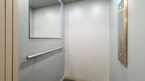 Un ascensor estrecho con barandilla y panel de control.
