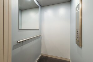 A narrow elevator with a handrail and a control panel. - Royal - by Kairos Apartments (Gliwice)
