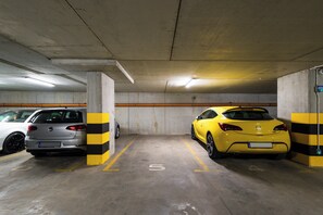 A parking garage with two cars parked in designated spaces. - Royal - by Kairos Apartments (Gliwice)