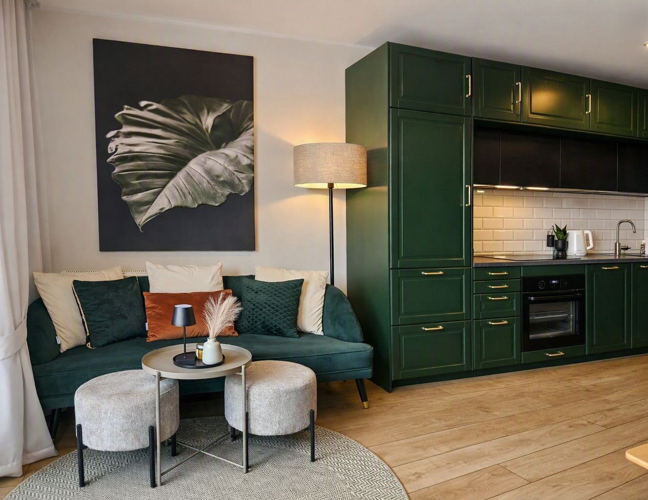 Een moderne woonkamer met een bank, een voetenbankje en een salontafel. Aan de muur hangt een schilderij en er staat een lamp naast de bank.