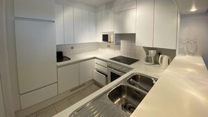 A modern kitchen with white cabinets, stainless steel appliances, and a double sink. - Seafront Palm Beach Stay (Knokke-Heist)