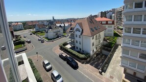 A residential area with a mix of modern and traditional architecture, including a prominent white building with a red roof and a tower-like structure in the background. - Apartment in Knokke Near the Beach (Knokke-Heist)