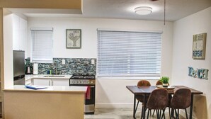 Una cocina moderna con estufa a gas, un fregadero y una encimera. Hay un comedor con una mesa y sillas.