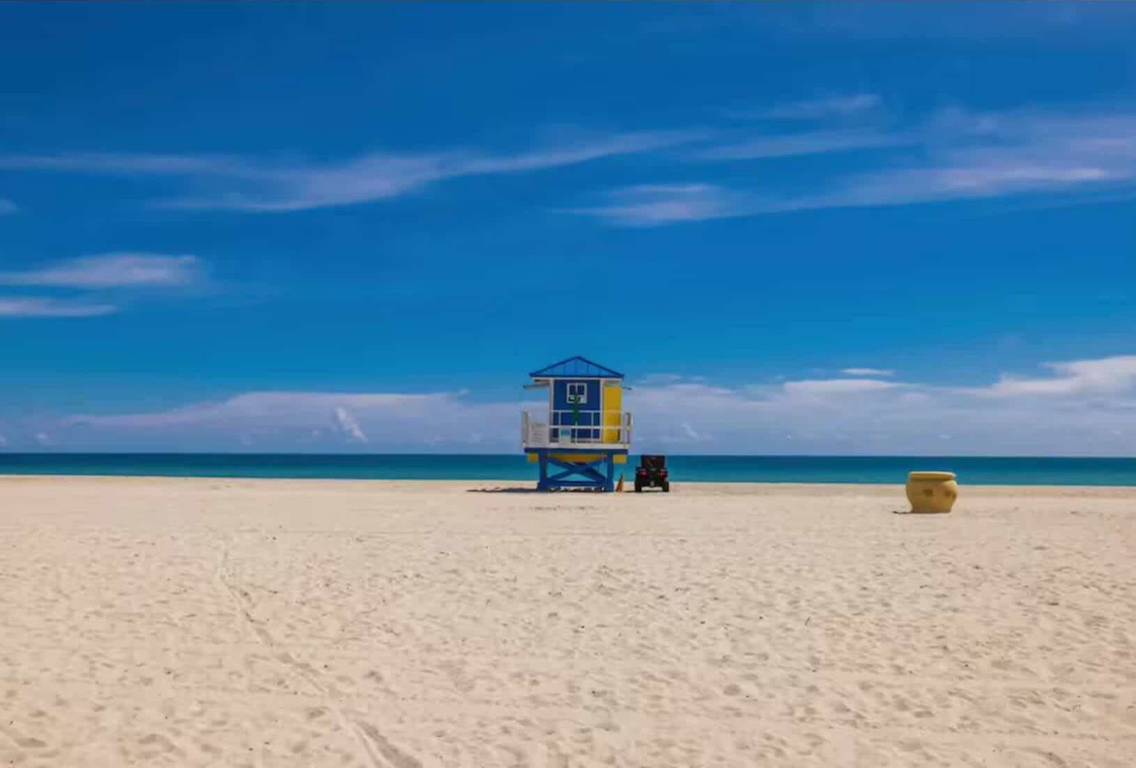 A lifeguard tower on a sandy beach with a clear blue sky.