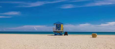 A lifeguard tower on a sandy beach with a clear blue sky.