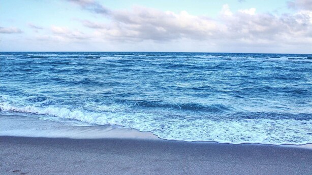 Una playa con olas acercándose a la orilla.