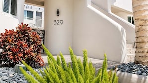 A modern building with a large number '329' on the wall, a staircase, and a well-maintained garden with red-leafed shrubs and green plants. - Hollywood Beach 1-Min Walk | King Bed | Beach Gear (Hollywood)