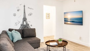A living room with a sofa, a coffee table, a framed picture, and a wall decal of the Eiffel Tower. - Hollywood Beach 1-Min Walk | King Bed | Beach Gear (Hollywood)
