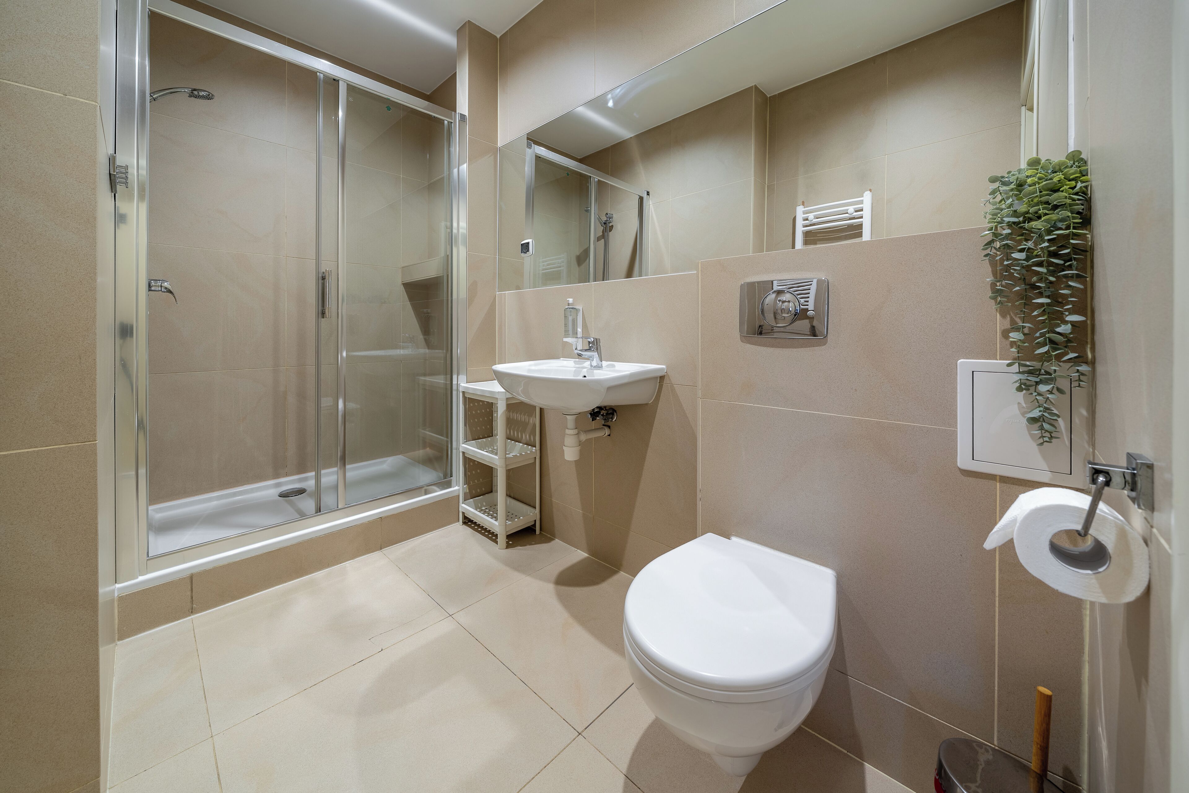 A modern bathroom with a glass-enclosed shower, a white sink, and a toilet.