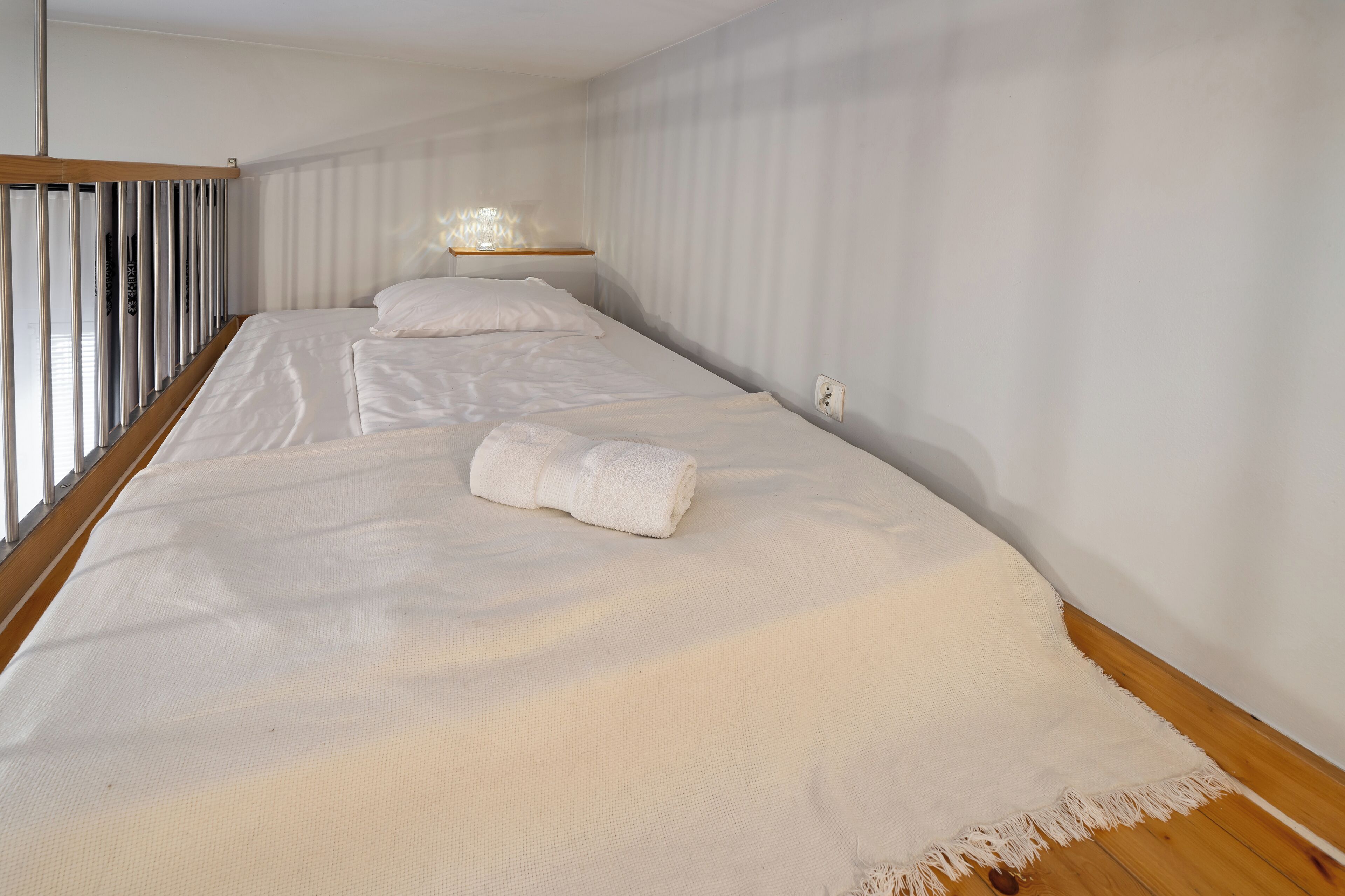 A bedroom with a large bed, a bedside table, and a window with blinds.