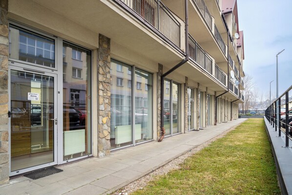 A modern building with large glass windows, stone pillars, and a flat roof. - RentPlanet - Apartamenty Brzozowa (Zakopane)