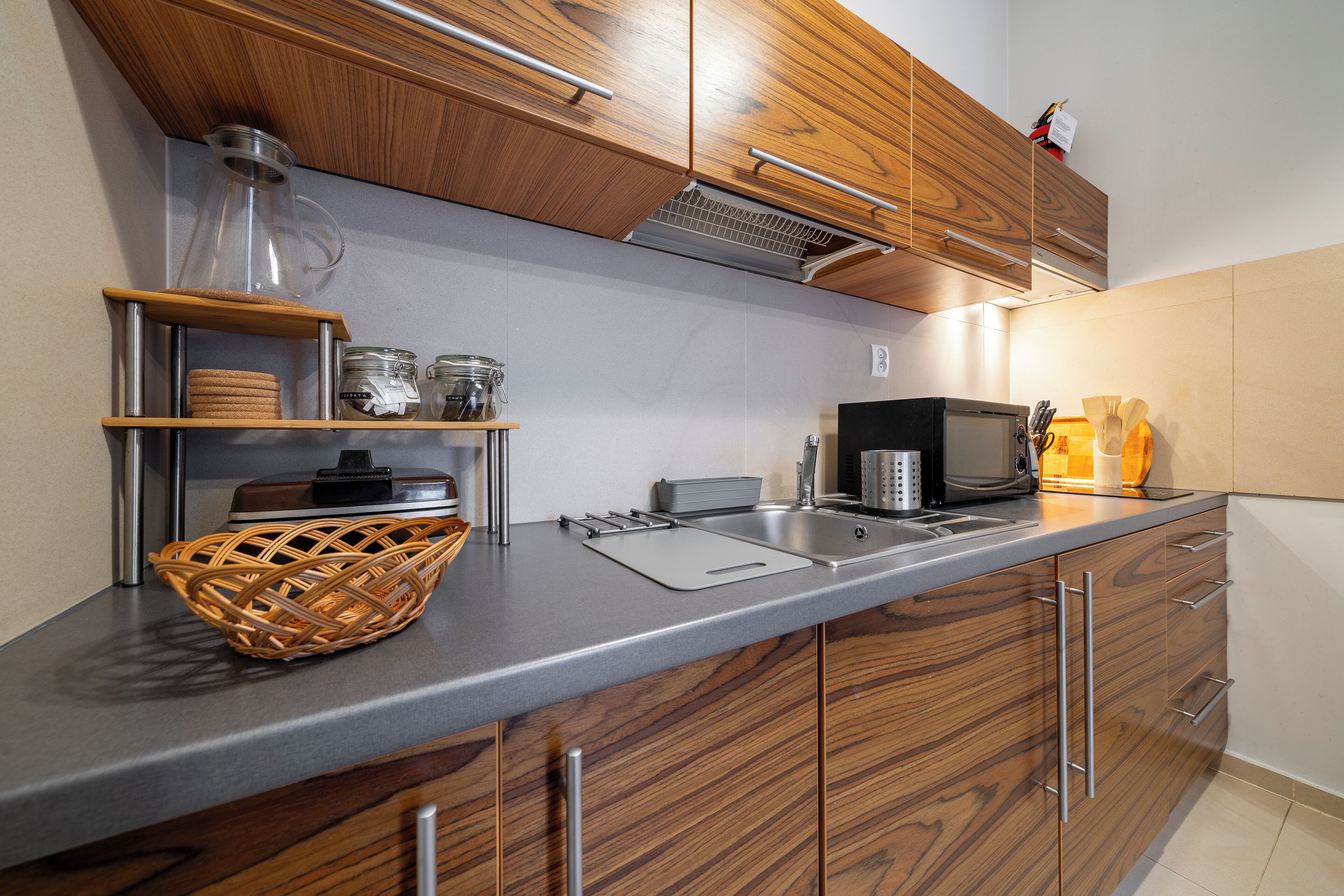 A modern kitchen with wooden cabinets, a stainless steel sink, and a microwave.