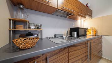 A modern kitchen with wooden cabinets, a stainless steel sink, and a microwave.