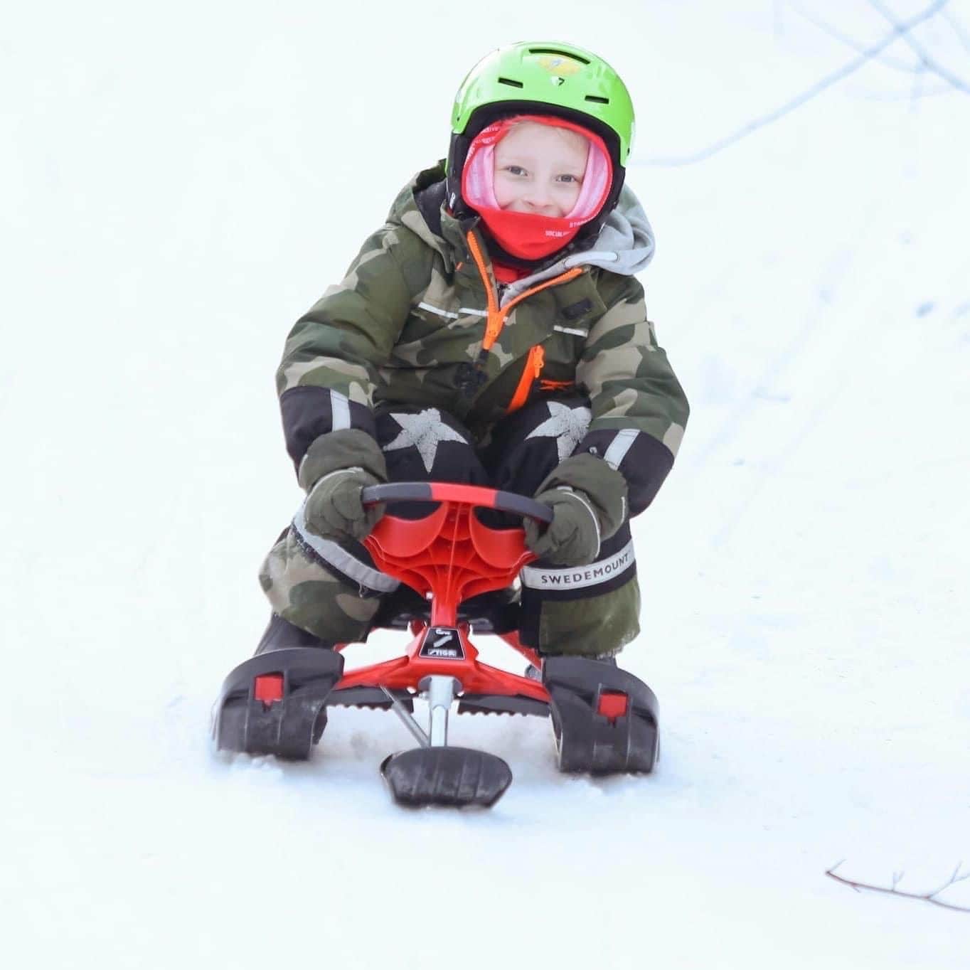 Un niño conduciendo un motor de nieve en un paisaje nevado.