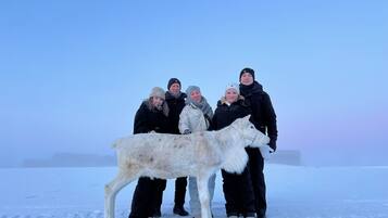 A group of people standing on a snowy surface with a large white dog in the foreground.